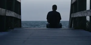 persona sentada en un puente frente al mar. Sobrepensar
