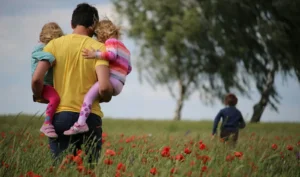 hombre cargando a sus hijos neurodivergentes