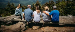 group of people sitting on rocks overlooking mountain. distanciamiento